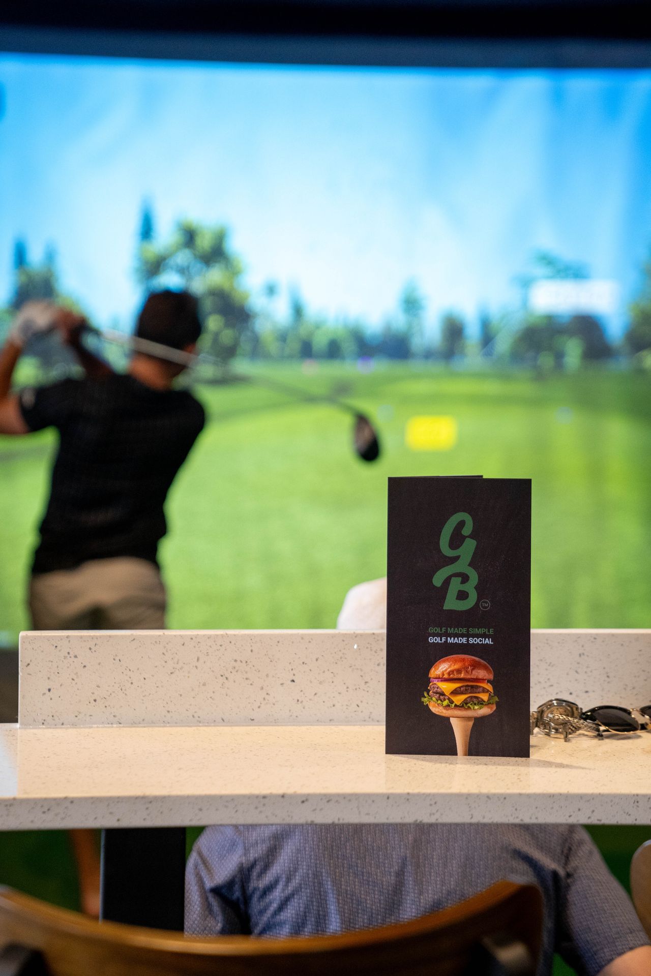 Golfer playing in an indoor golf simulator at Green Bird in Flower Mound, TX